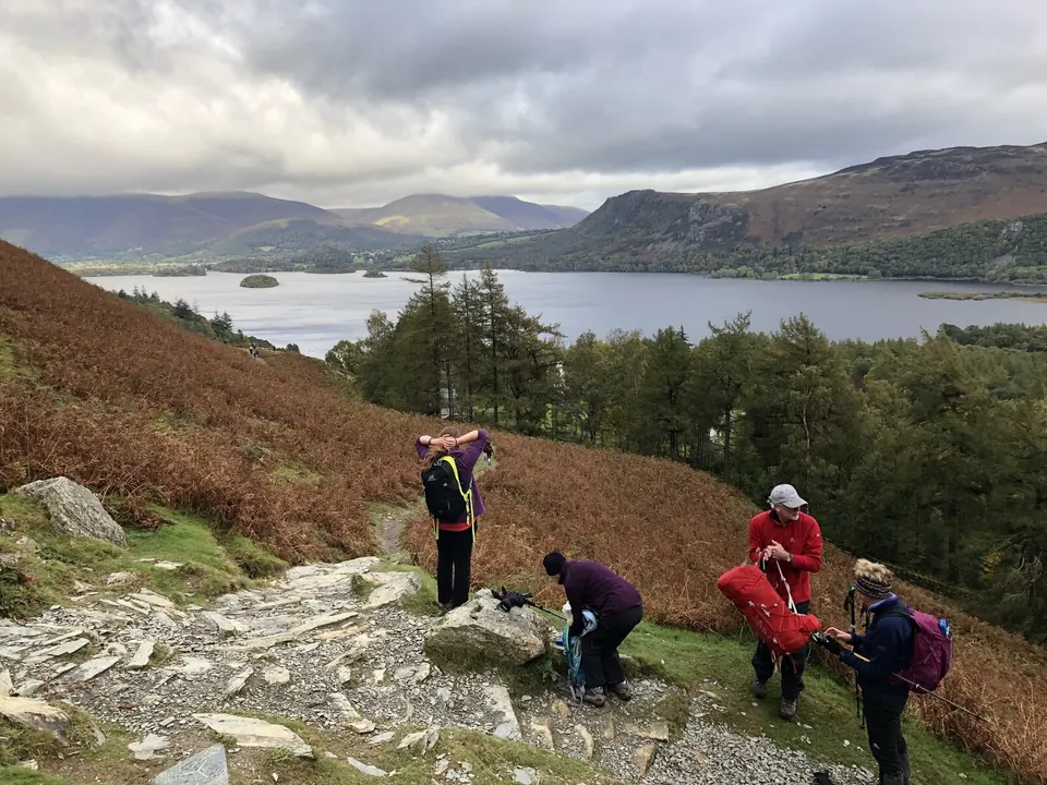 Walkers on a rocky path among autumn bracken coming down Catbells towards Derwentwater